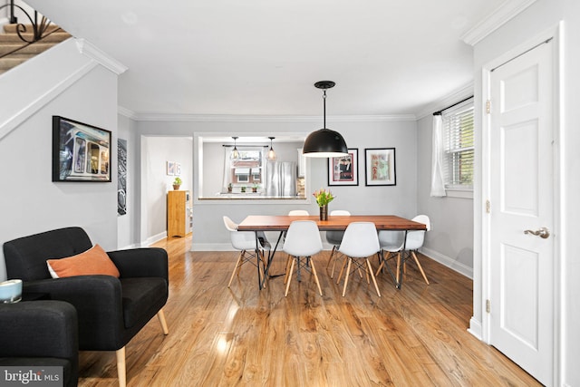 dining room with baseboards, ornamental molding, and light wood-type flooring