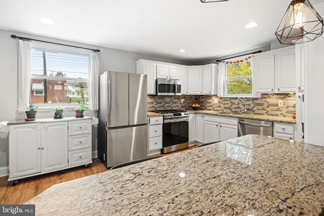 kitchen featuring a sink, backsplash, stainless steel appliances, and white cabinetry