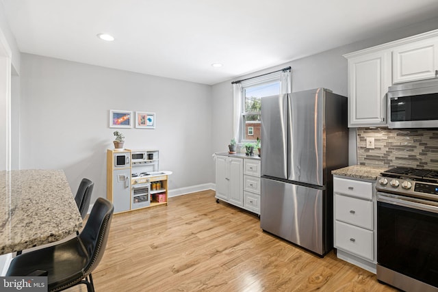 kitchen with decorative backsplash, light wood-style flooring, appliances with stainless steel finishes, and white cabinets