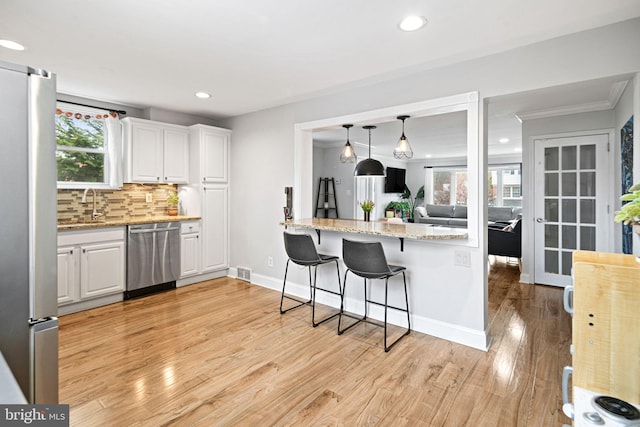 kitchen featuring visible vents, appliances with stainless steel finishes, tasteful backsplash, white cabinets, and light wood-style flooring