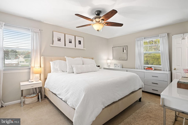bedroom featuring light colored carpet, baseboards, and ceiling fan