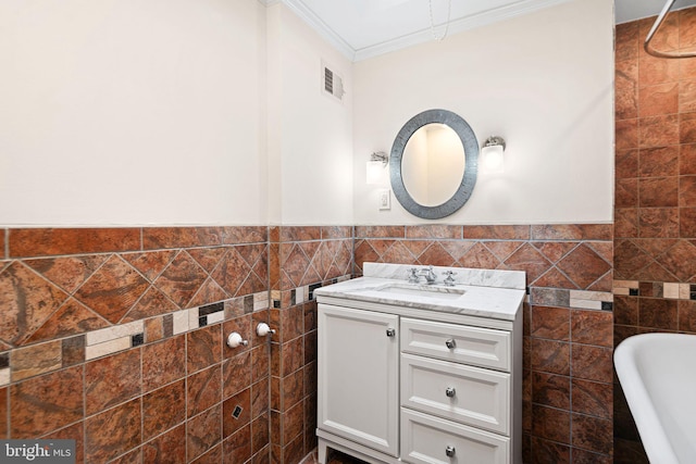 bathroom featuring crown molding, vanity, tile walls, visible vents, and a bath