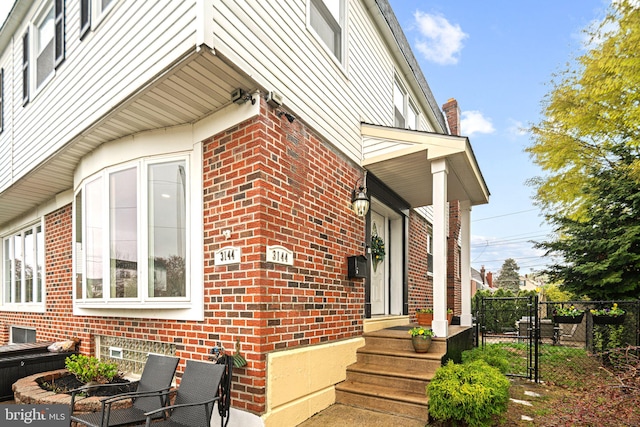 view of home's exterior featuring brick siding, fence, and a gate