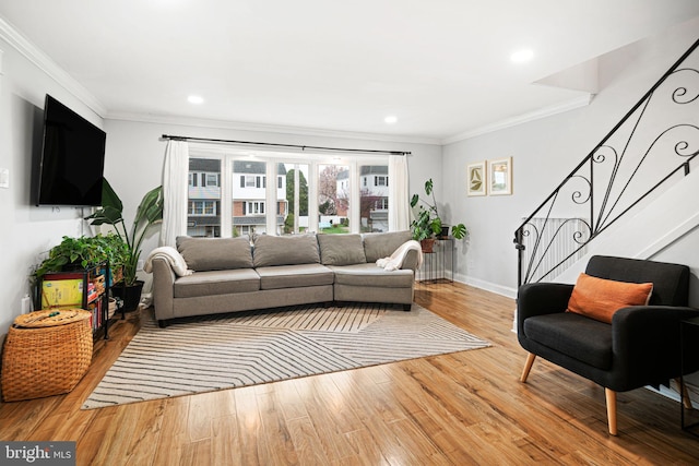 living room with crown molding, baseboards, stairs, and wood finished floors