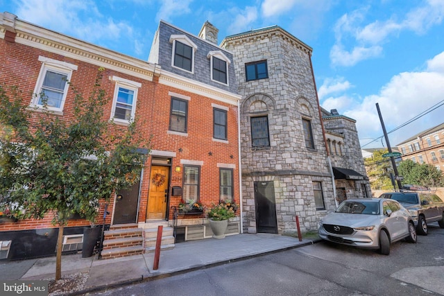 view of property with brick siding, mansard roof, and entry steps