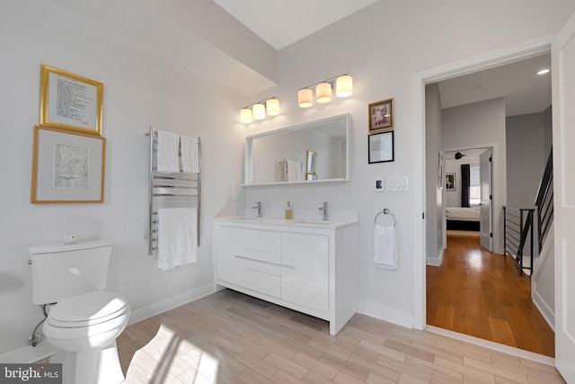 ensuite bathroom with toilet, baseboards, wood finished floors, and ensuite bathroom