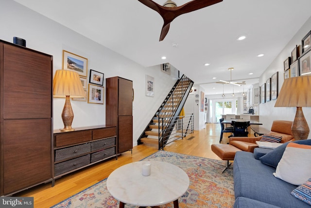 living room featuring recessed lighting, a ceiling fan, light wood-style flooring, and stairway