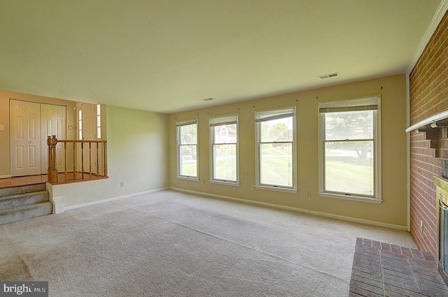 unfurnished living room with a brick fireplace, light carpet, healthy amount of natural light, and baseboards