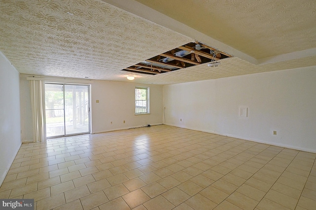 spare room featuring a textured ceiling, tile patterned flooring, and baseboards