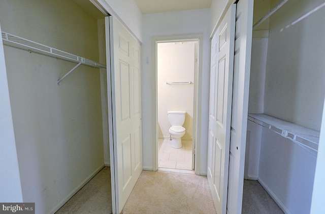 bathroom with toilet, a closet, and baseboards