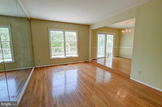 unfurnished room featuring hardwood / wood-style flooring, a chandelier, and healthy amount of natural light