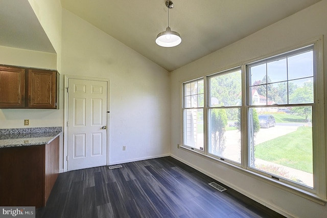 unfurnished dining area featuring vaulted ceiling, dark wood finished floors, and baseboards