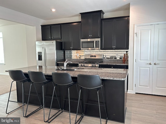 1108 Dovetail Cir, Fredericksburg, VA 22401 - kitchen with stainless steel appliances, dark cabinetry, an island with sink, light stone countertops, and recessed lighting