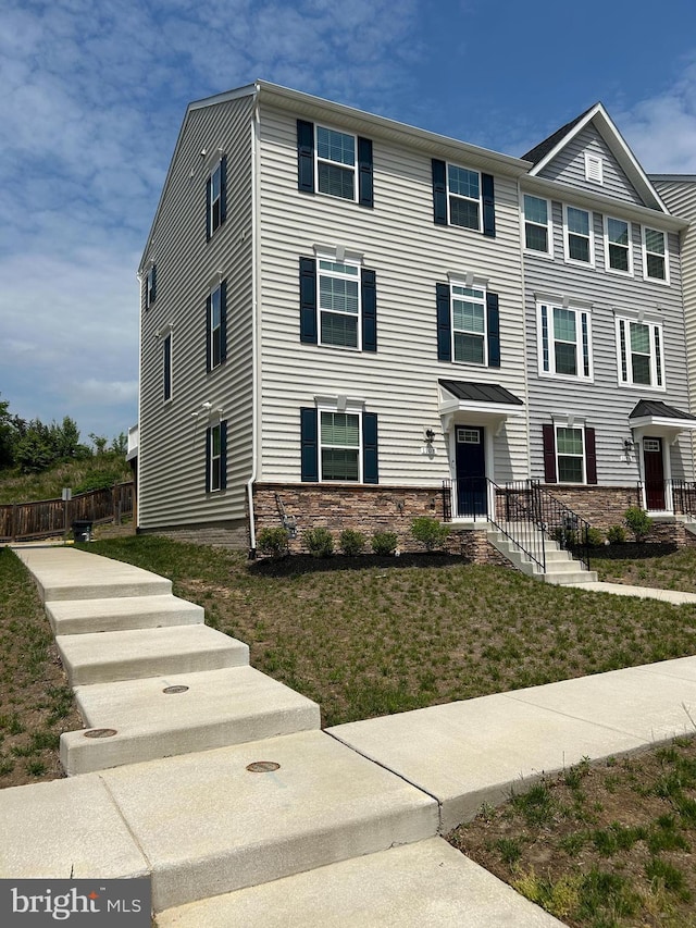 multi unit property featuring a front lawn, fence, and stone siding