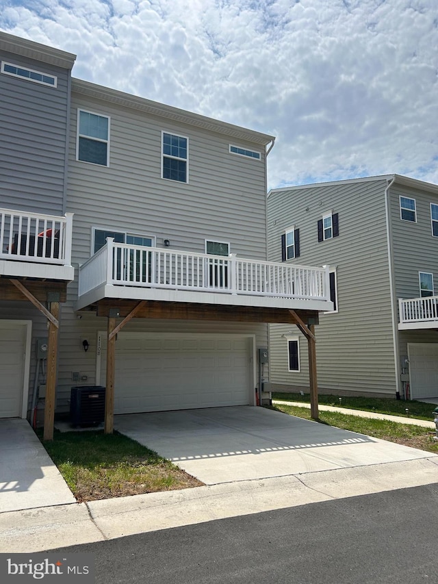 exterior space with central air condition unit, an attached garage, and driveway
