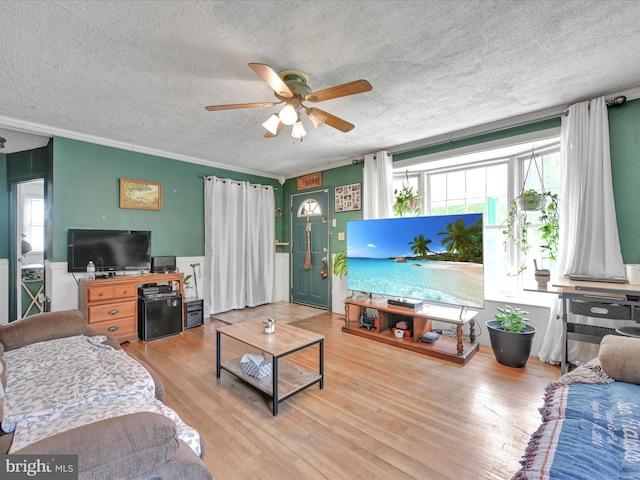 living room with a ceiling fan, a textured ceiling, a healthy amount of sunlight, and wood finished floors