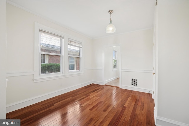 empty room featuring baseboards, hardwood / wood-style floors, and crown molding