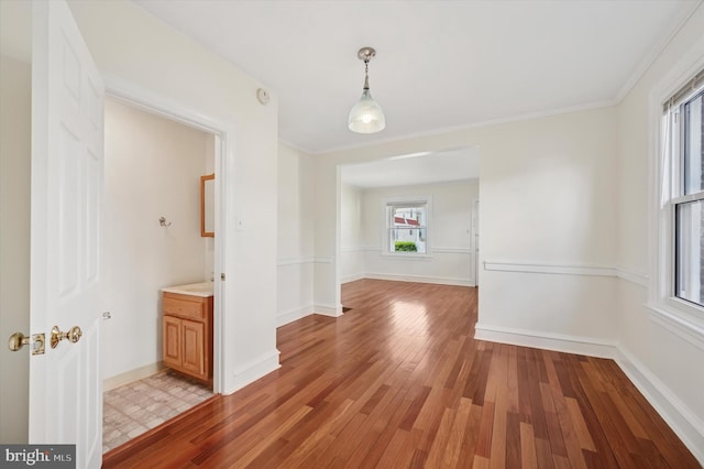 unfurnished dining area with crown molding, light wood-style flooring, and baseboards