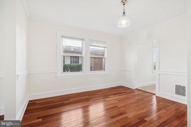 empty room with ornamental molding, hardwood / wood-style floors, and visible vents