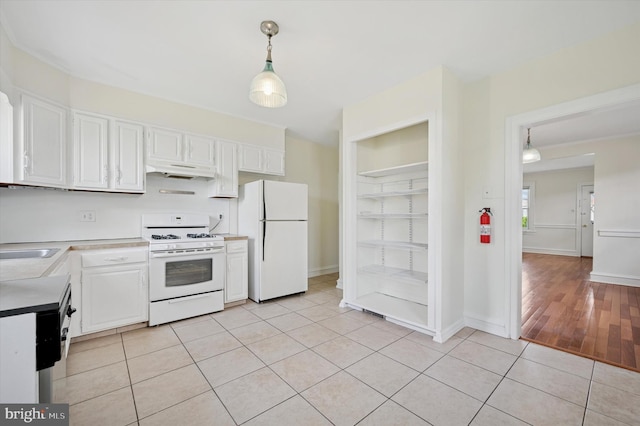 kitchen featuring under cabinet range hood, light tile patterned floors, white appliances, light countertops, and white cabinets