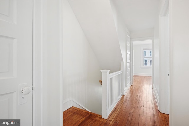 hall featuring hardwood / wood-style flooring, baseboards, and an upstairs landing