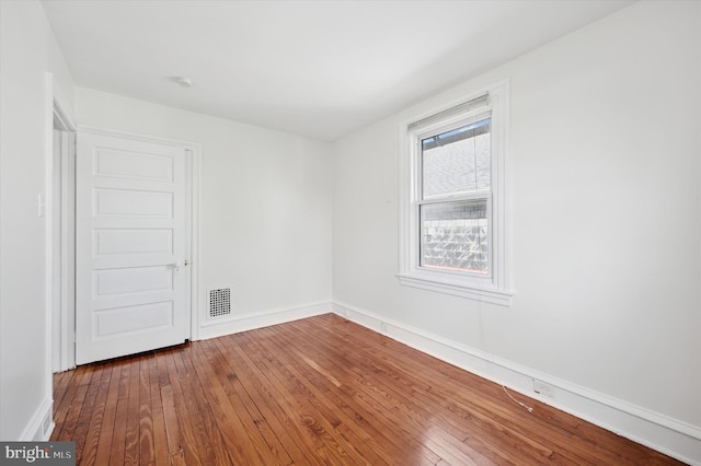 unfurnished room featuring baseboards, visible vents, and hardwood / wood-style flooring