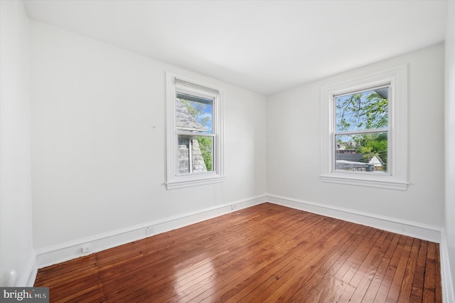 unfurnished room with baseboards and hardwood / wood-style flooring