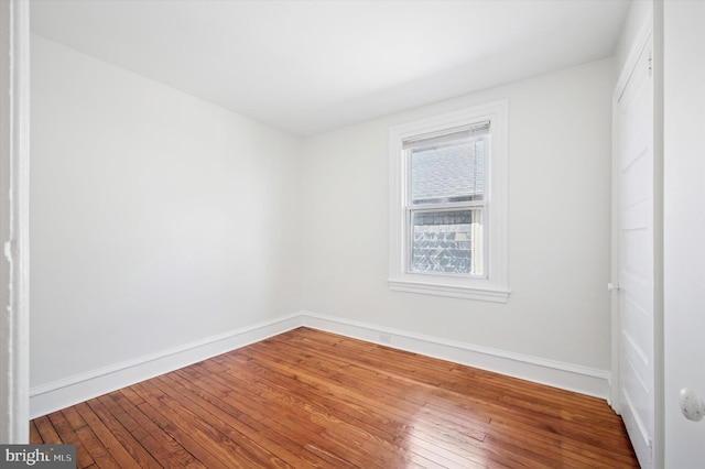 empty room featuring baseboards and wood-type flooring