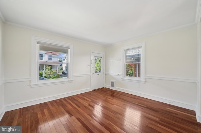 spare room with baseboards, ornamental molding, visible vents, and hardwood / wood-style flooring