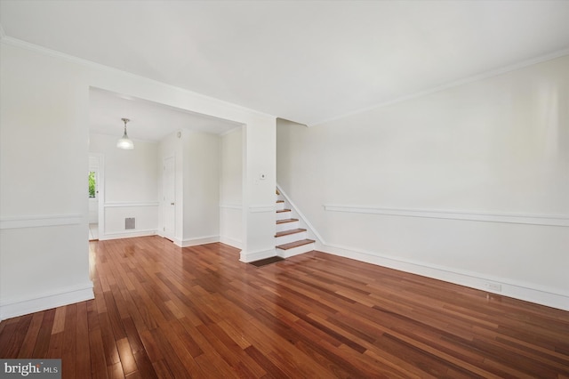 empty room with stairs, hardwood / wood-style floors, visible vents, crown molding, and baseboards