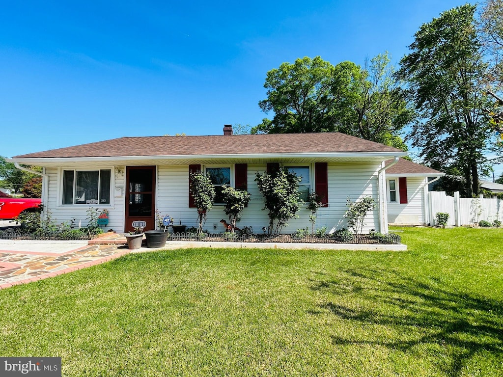 ranch-style home with a chimney, fence, and a front yard