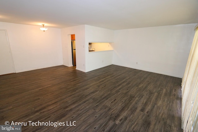 empty room featuring baseboards and dark wood finished floors