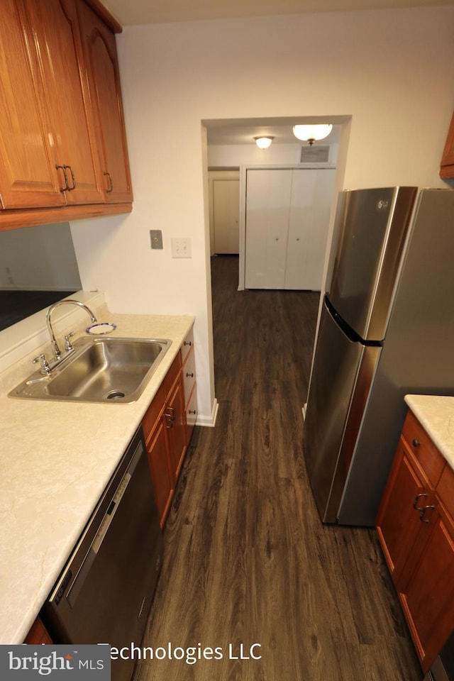kitchen with light countertops, appliances with stainless steel finishes, a sink, and dark wood-type flooring
