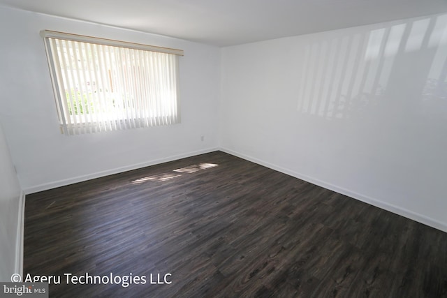 spare room with dark wood-style flooring and baseboards