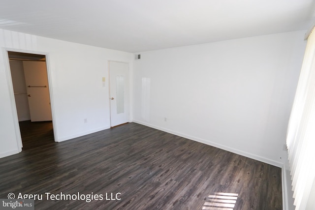 unfurnished bedroom featuring dark wood-type flooring, baseboards, a walk in closet, and visible vents