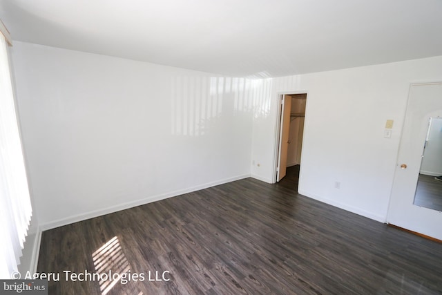 unfurnished room with baseboards and dark wood-style flooring