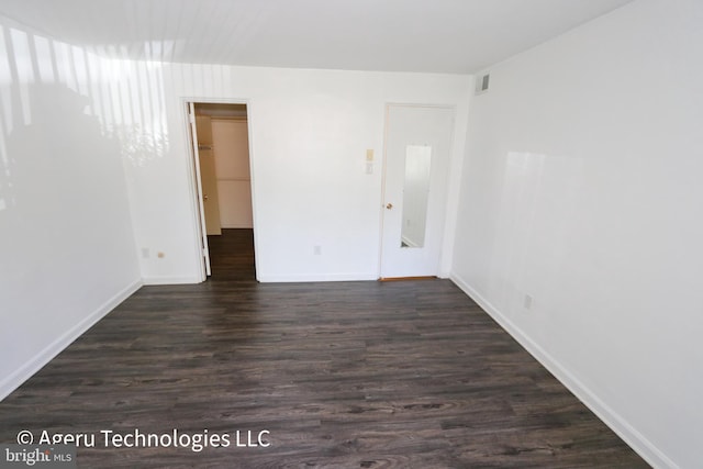 spare room featuring baseboards, visible vents, and dark wood-style floors