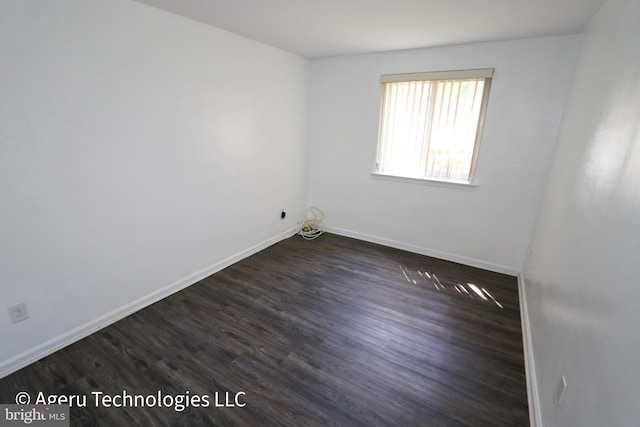 unfurnished room featuring baseboards and dark wood-type flooring