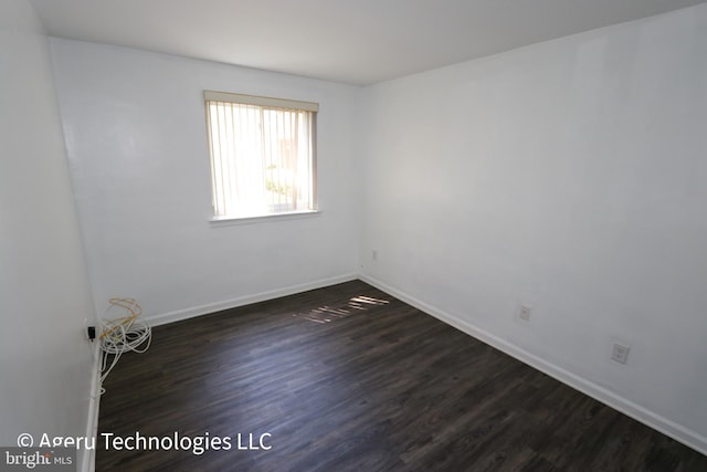 empty room featuring baseboards and dark wood-style floors