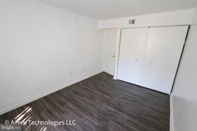 unfurnished bedroom with visible vents, baseboards, wood finished floors, and a closet