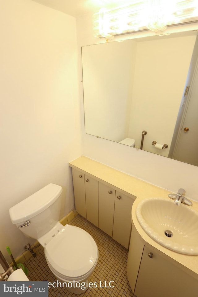 half bathroom featuring vanity, tile patterned flooring, and toilet
