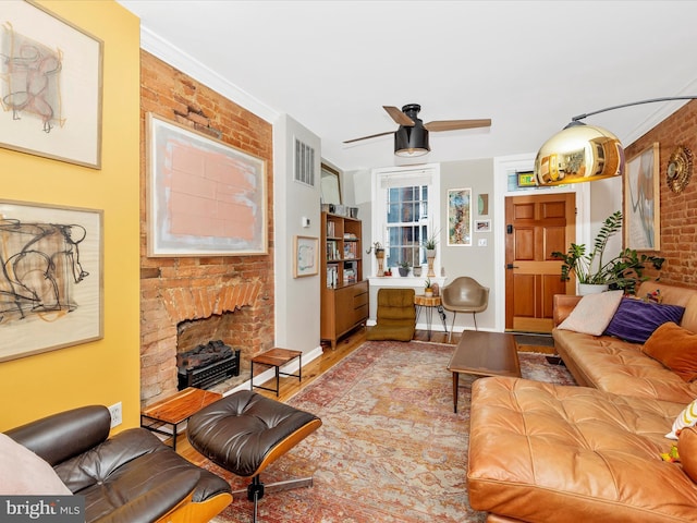 living room with brick wall, a fireplace, wood finished floors, and ceiling fan