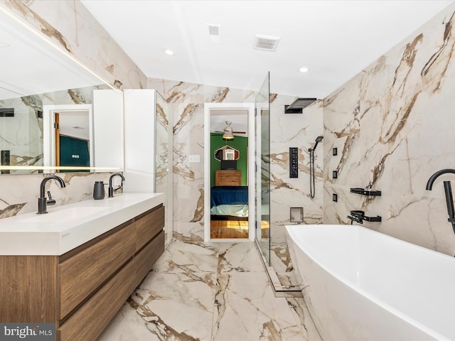 bathroom with stone wall, a freestanding bath, double vanity, marble tiled floors, and a marble finish shower
