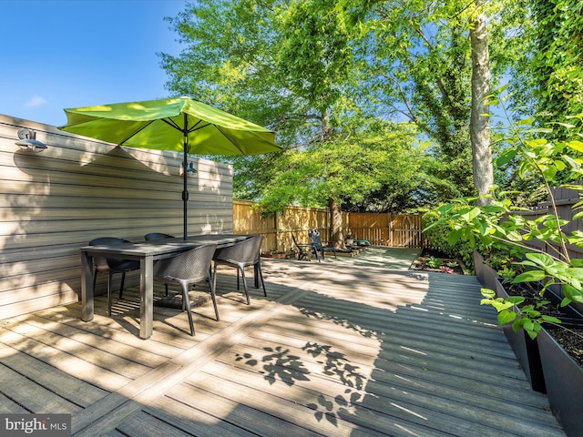 deck featuring outdoor dining area and a fenced backyard