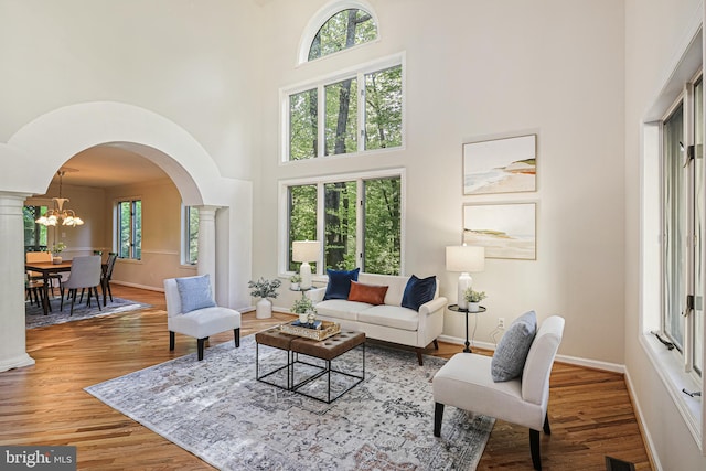 living room with arched walkways, a high ceiling, baseboards, and wood finished floors