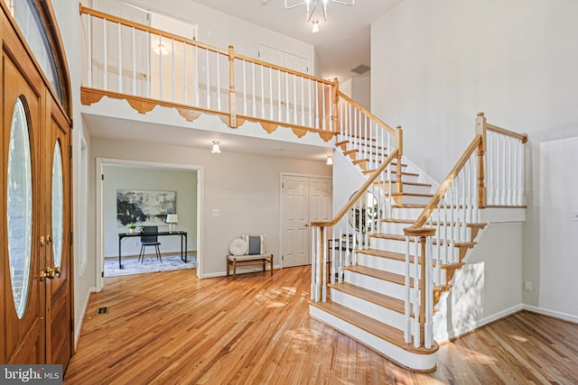 stairway with baseboards, a towering ceiling, wood finished floors, and visible vents