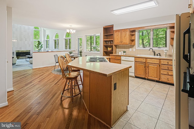 kitchen featuring open shelves, a sink, white appliances, light countertops, and a kitchen island