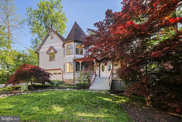 victorian house with an attached garage and a front yard