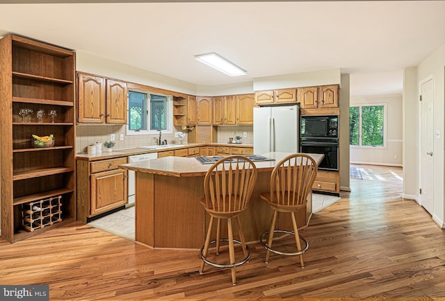 kitchen featuring a kitchen island, open shelves, black appliances, and tasteful backsplash