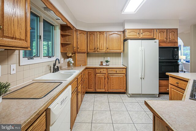 kitchen with brown cabinetry, a sink, decorative backsplash, and black appliances